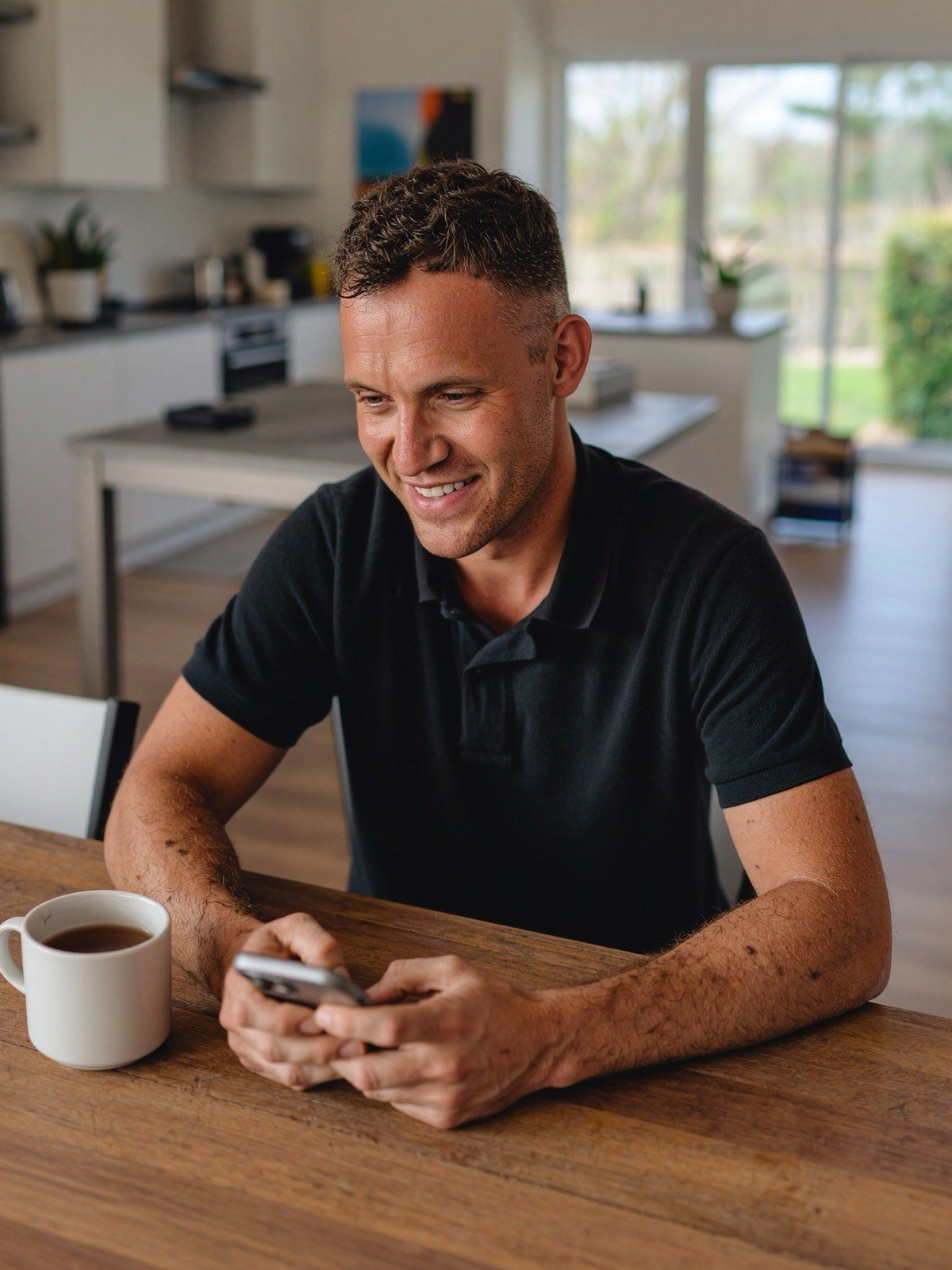 An electrician on his phone in a kitchen, pricing a job between fixes